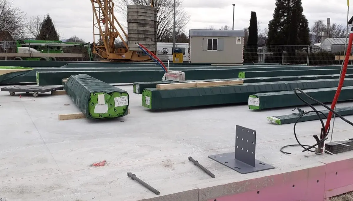 Angelieferte und noch verpackte Holzbalken liegen auf dem Fundament der zukünftigen Kletterhalle. | © DAV Sektion Hohenstaufen Göppingen