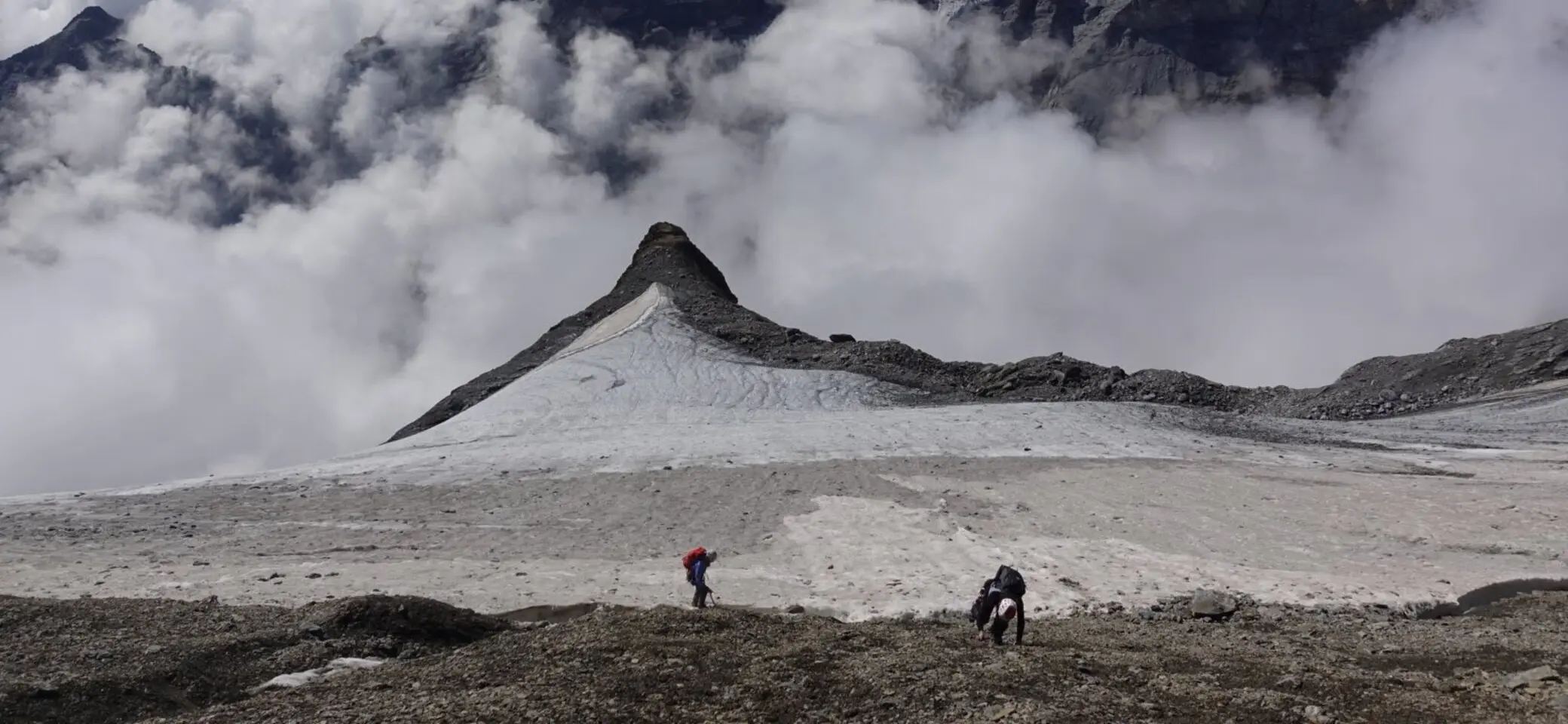 Zwei Bergsteiger auf dem Weg zum Gipfel in einer wolkenverhangenen Bergkulisse | © Pete Parker Photography