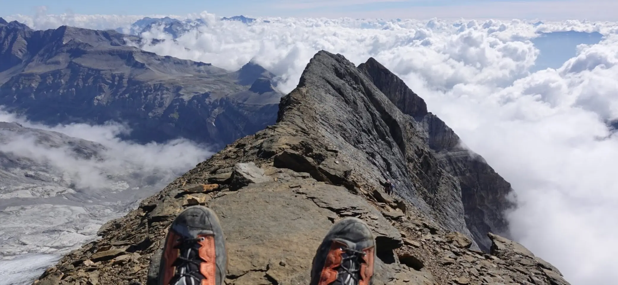 Schuhspitzen von Wanderschuhen auf dem Gipfel. Im Hintergrund ein imposantes Gipfelpanorama im Nebel. | © Pete Parker Photography