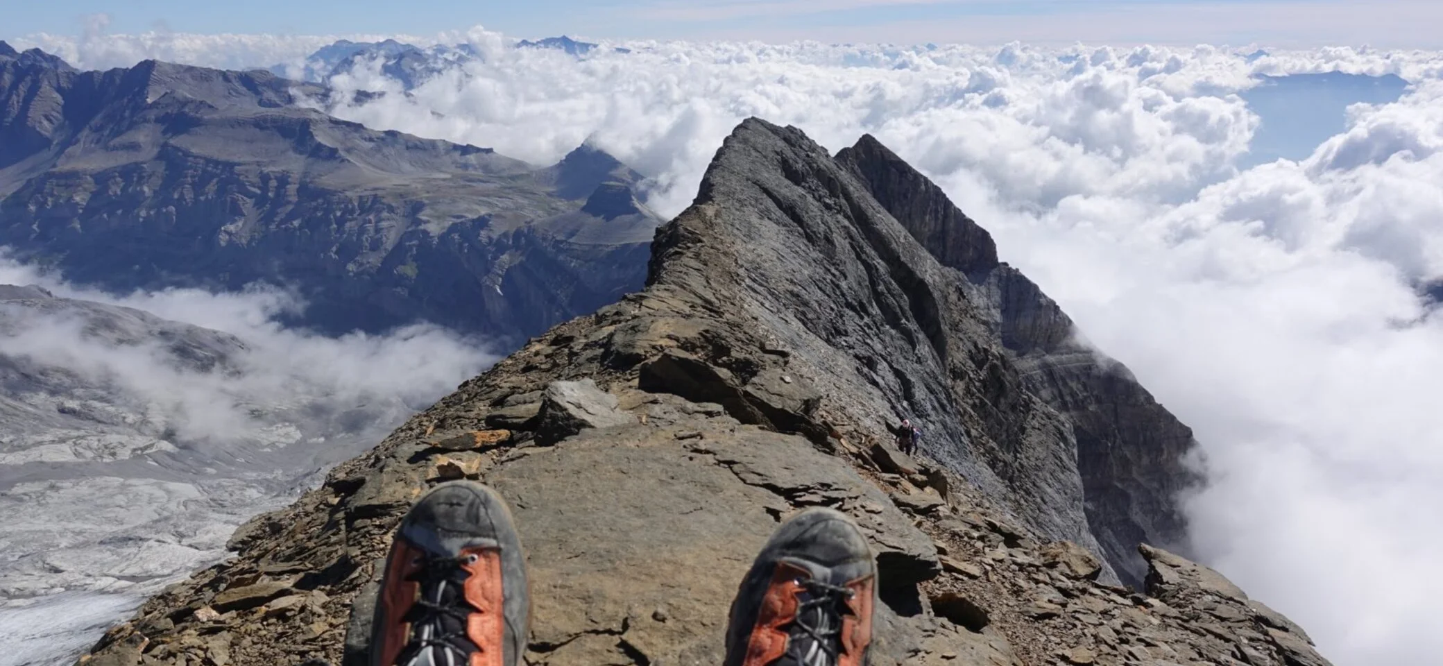 Schuhspitzen von Wanderschuhen auf dem Gipfel. Im Hintergrund ein imposantes Gipfelpanorama im Nebel. | © Pete Parker Photography