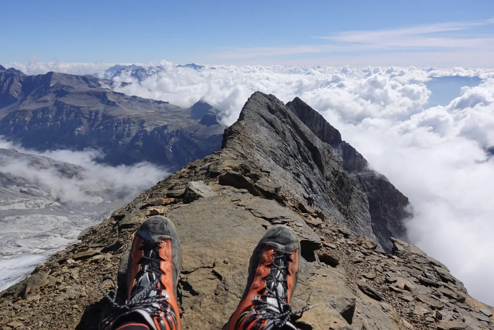 Schuhspitzen von Wanderschuhen auf dem Gipfel. Im Hintergrund ein imposantes Gipfelpanorama im Nebel. | © Pete Parker Photography