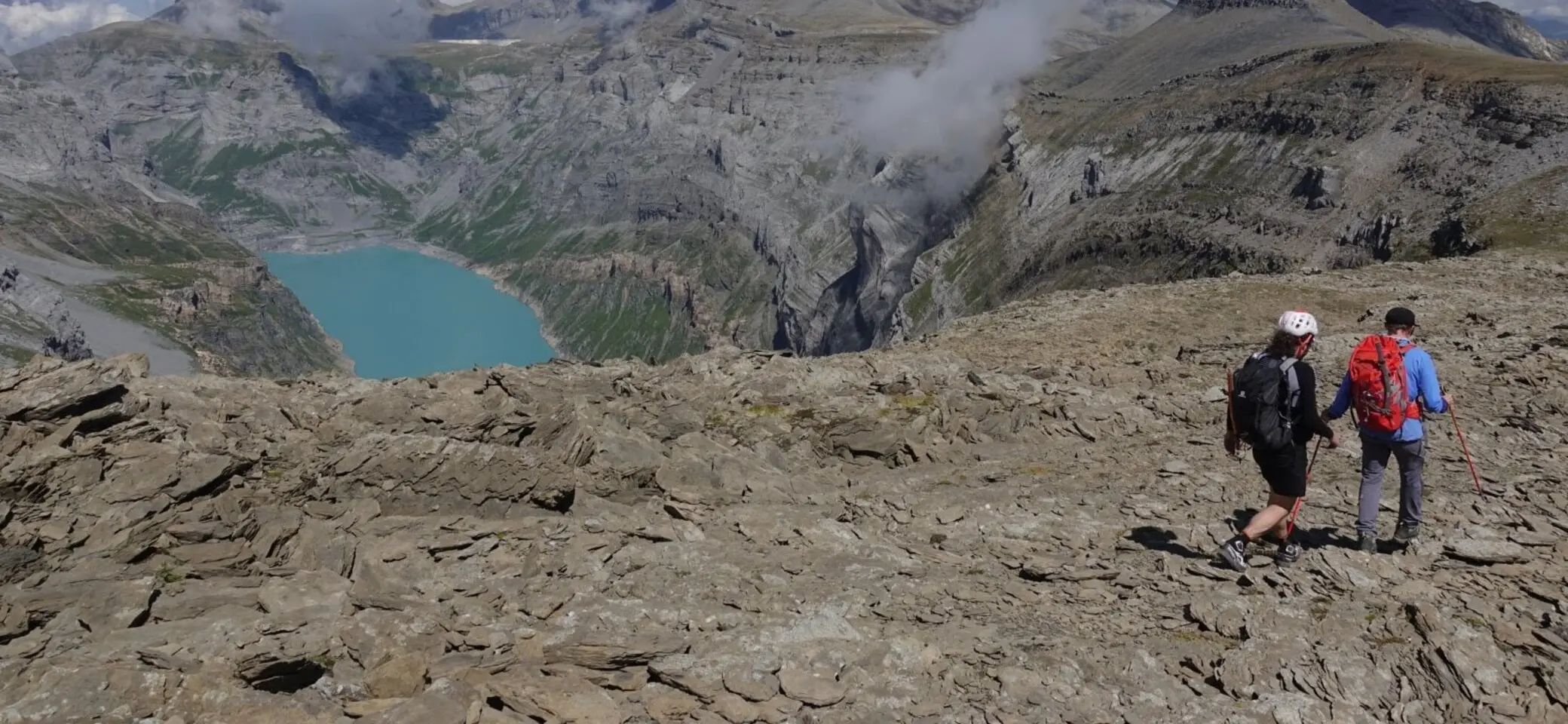 Zwei Bergsteiger wandern auf dem Rückweg vom Gipfel an einem Bergsee vorbei | © Pete Parker Photography