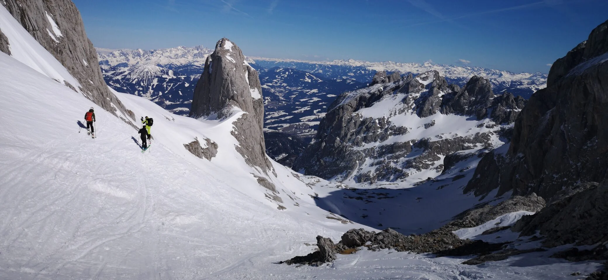 Mehrere Skifahrer auf dem Rückweg vom Gipfel einer Skihochtour. Vor ihnen liegt ein schneeverschneites Bergpanorama. | © Pete Parker Photography