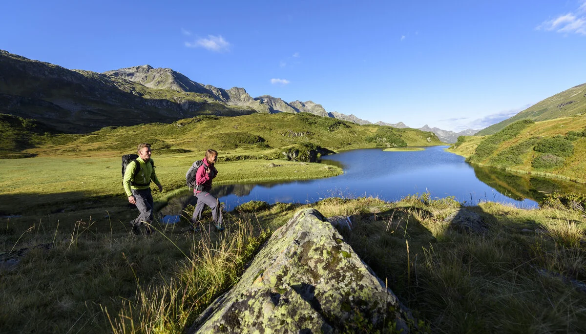 Wanderer im Frühling - im Hintergrund ein Bergsee | © DAV/Wolfgang Ehn